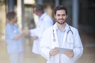 Portrait of smiling doctor standing with digital tablet