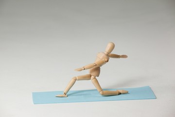 Wooden figurine exercising on exercise mat