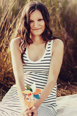 Fototapeta premium Pregnant woman holding colorful windmill on forest background