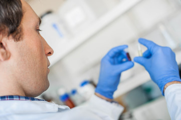 Fototapeta premium Male lab technician holding a test tube with sample