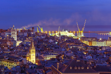 Aerial view of old town and port with cranes at night, Genoa, Italy.