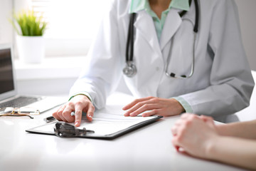 Close up of doctor and  patient  sitting at the desk near the window in hospital