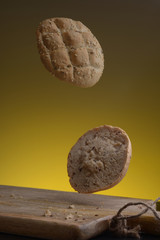 Cutting a bun with sesame seeds in flight on a yellow background.
