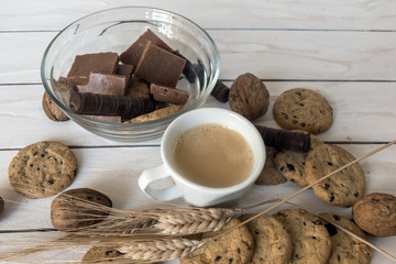 Cup of coffee, cookies, walnut and chocolate on the white wooden background
