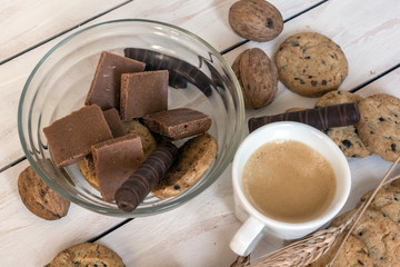 Cup of coffee, cookies, walnut and chocolate on the white wooden background

