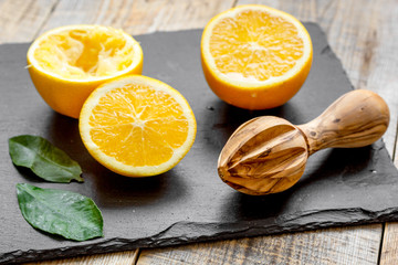 cut oranges in half and juicer on wooden background