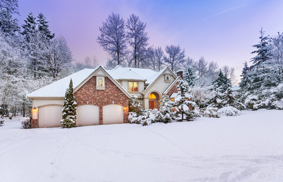 Driveway view of snowy home - daylight fades over a snow-covered suburban home