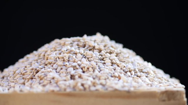 Rotating sesame seed in wooden bowl.