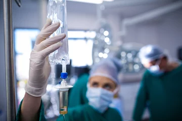 Fotobehang Female surgeons adjusting iv drip in operation theater © WavebreakMediaMicro