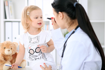 Pediatrician is taking care of baby in hospital. Little girl is being examine by doctor with stethoscope. Health care, insurance and help concept.