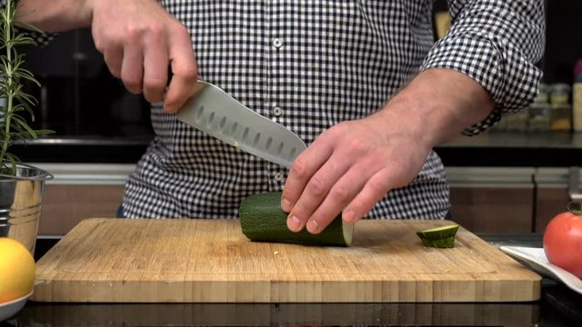 Close up on man's hands cutting courgette.
