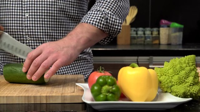 Close up on man's hands cutting courgette. Slider shot.
