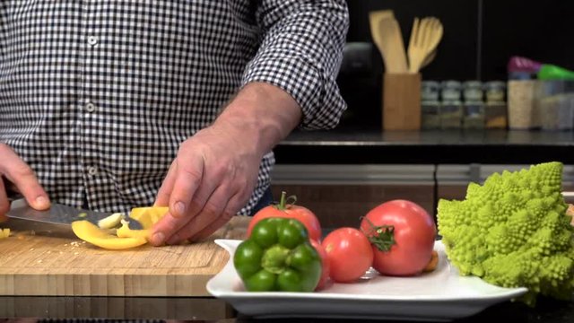 Close up on man's hands cleansing and cutting pepper. Slider shot.
