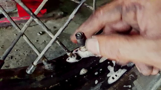 closeup macro man fingers bind nipple on motorcycle wheel tire disk in repair-shop