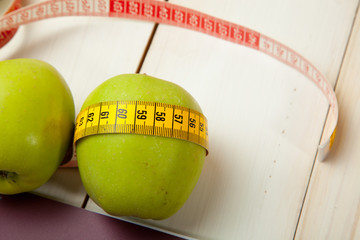 Green apples with measuring tape on a white wooden table
