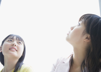 Smiling two young women looking up