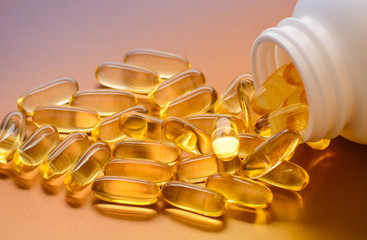 Fish oil capsules with omega 3 and vitamin D in a plastic bottle on a shiny texture, healthy diet...