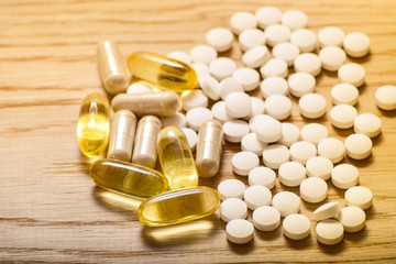 Fish oil capsules with omega 3 and vitamin supplements on a wooden texture, healthy diet concept