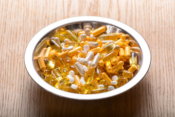 Fish oil capsules with omega 3 and vitamin supplements on a wooden texture, healthy diet concept