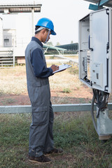engineer or electrician working on checking and maintenance equipment at green energy solar power plant: checking status inverter
