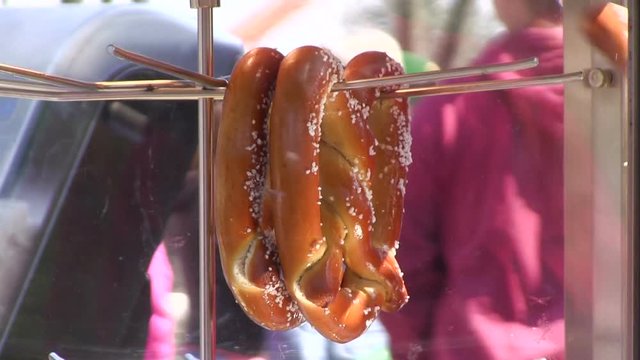 Soft pretzel hanging on rack rotating in oven.