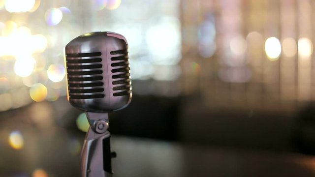Close-up of retro microphone with blurred lights at background. Concert microphone stand on stage in retro club. 