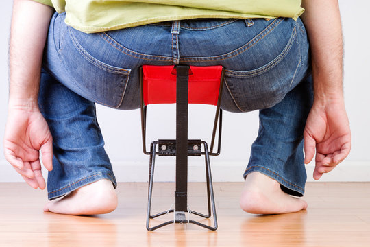 Overweight Barefoot Man Sat On Tiny Chair