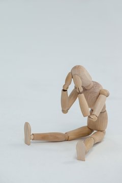 Tensed wooden figurine sitting with hands on head