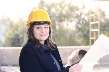 Female architect at a construction site with blueprints.