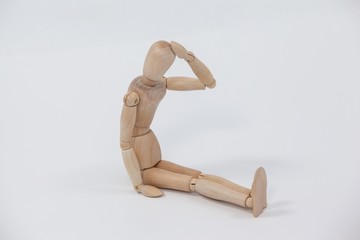 Tensed wooden figurine sitting with hand on head