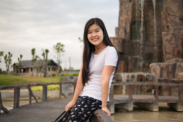Asian woman sitting on the fence and smile