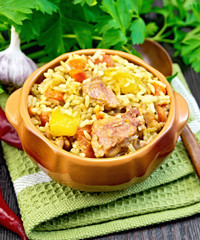 Rice with chicken and zucchini in clay bowl on dark board