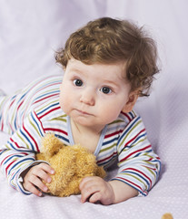 The little boy in the crib with toys. The child in the home
