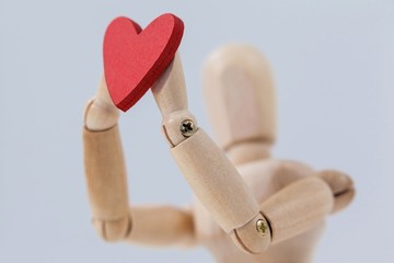 Wooden figurine holding a red heart 