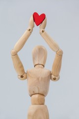 Wooden figurine standing and holding a red heart on top