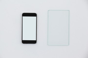 Sheet of glass and mobile phone on white background
