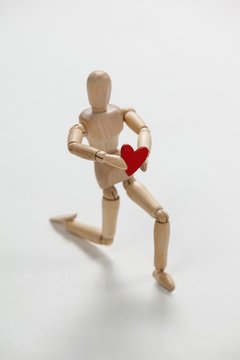 Wooden figurine kneeling and holding a red heart