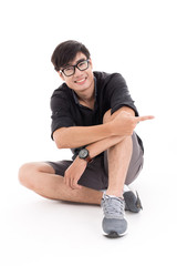 Naklejka premium Young man sitting on the floor, pointing and looking to his side