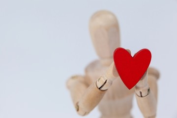Wooden figurine holding a red heart