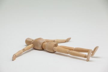 Wooden figurine lying on floor with arms spread