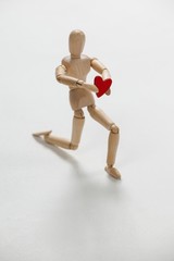 Wooden figurine kneeling and holding a red heart