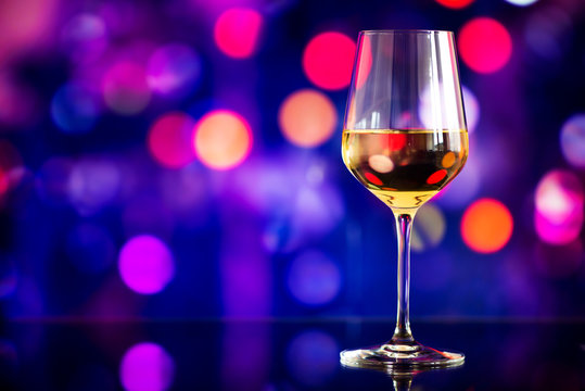 glass of white wine against a glowing bokeh - copy space, select