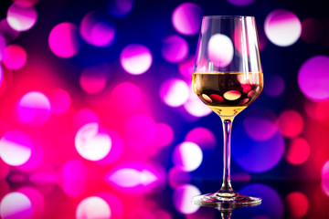 glass of white wine against a glowing bokeh - copy space, select