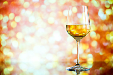 glass of white wine against a glowing bokeh - copy space, select