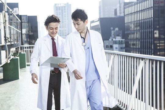 Two doctors are talking on the roof while watching the medical record