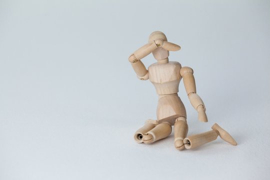 Wooden figurine sitting with hand on head