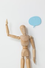 Thoughtful wooden figurine standing with hand raised