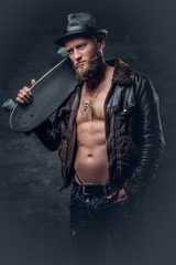 Fototapeta na wymiar Bearded male dressed in leather jackett holds skateboard.