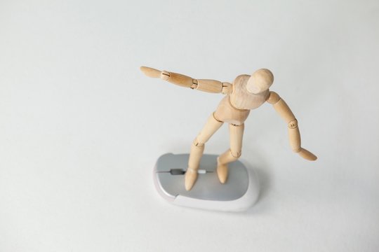 Wooden figurine standing with arms spread on a mouse