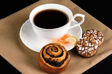 Cup of coffee and cookies close up on a black background.
